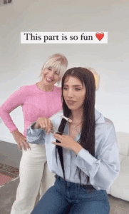 Screenshot of a Video Pin showing a woman with long brown hair sitting on a chair about to cut a section of her hair off with the hairdresser standing behind her and smiling. Text overlay says "This part is so fun."