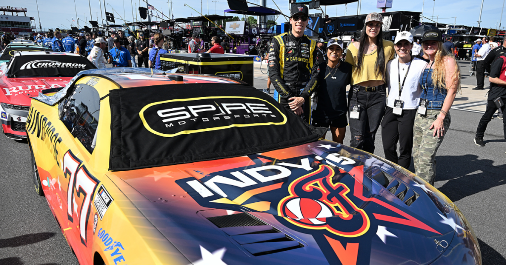 USL Super League players and NASCAR drivers around a Gainbridge-branded WNBA All-Star car